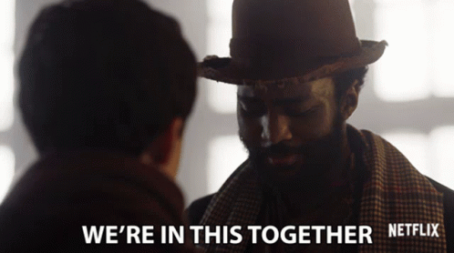 A Man Wearing A Hat And Scarf Talks To Another Man With The Words " We 'Re In This Together " Below Him GIF