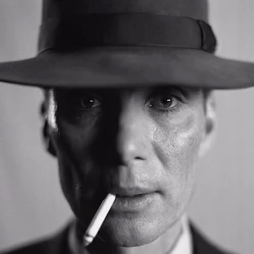A Man Wearing A Hat And Smoking A Cigarette In A Black And White Photo . GIF