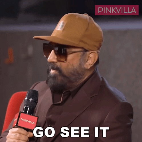 A Man Wearing A Hat And Sunglasses Is Holding A Microphone And Says Go See It GIF