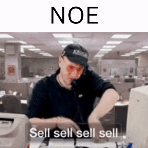 A Man Wearing A Hat And Sunglasses Is Sitting At A Desk Talking On A Cell Phone . GIF