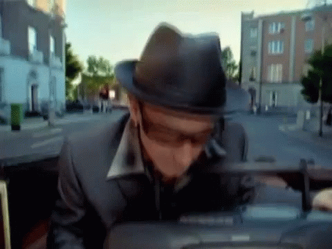 a man wearing a hat and sunglasses is sitting in the back seat of a car