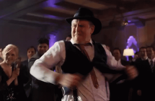 A Man Wearing A Hat And Suspenders Is Dancing At A Party GIF