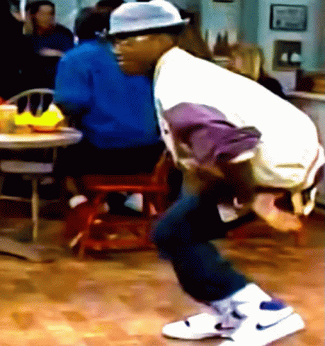 A Man Wearing A Hat And White Nike Shoes Is Squatting On The Floor GIF