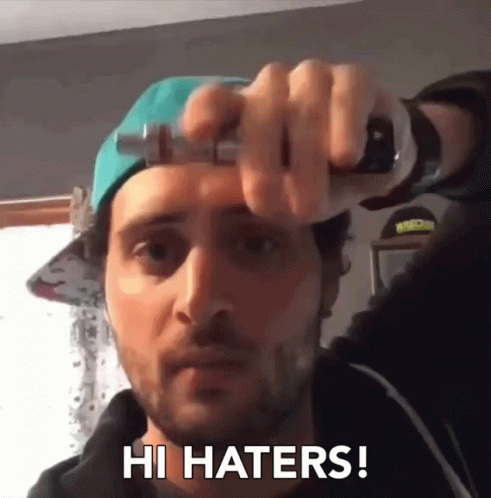 A Man Wearing A Hat Is Holding A Bottle And Saying Hi Haters GIF