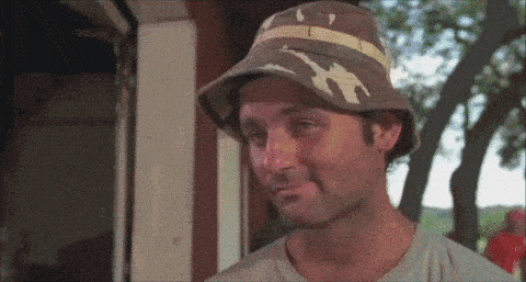 A Man Wearing A Hat Is Making A Funny Face And Smiling . GIF