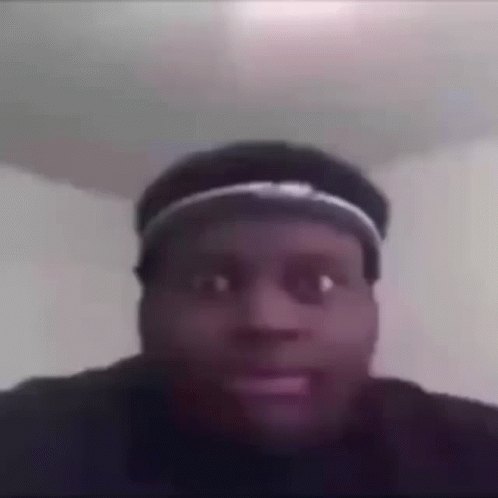 A Man Wearing A Hat Is Making A Funny Face In A Room . GIF