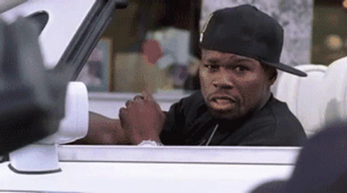 A Man Wearing A Hat Is Sitting In A Car And Looking Out The Window . GIF