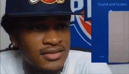 A Man Wearing A Hat Is Sitting In Front Of A Sign That Says ' Sound And Screen ' GIF