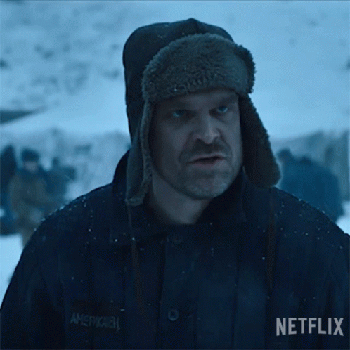 A Man Wearing A Hat Is Standing In The Snow With A Group Of People In The Background . GIF