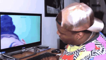 A Man Wearing A Hat Looks At A Computer Monitor GIF