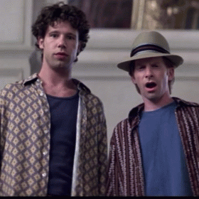 A Man Wearing A Hat Stands Next To Another Man GIF