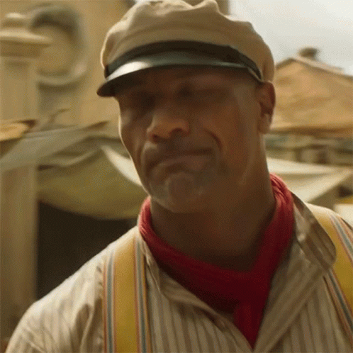 a man wearing a hat , suspenders and a red scarf is smiling .