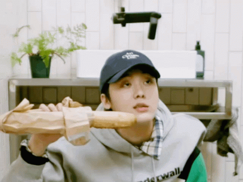 a man wearing a hat that says " air " on it holds a loaf of bread over his shoulder