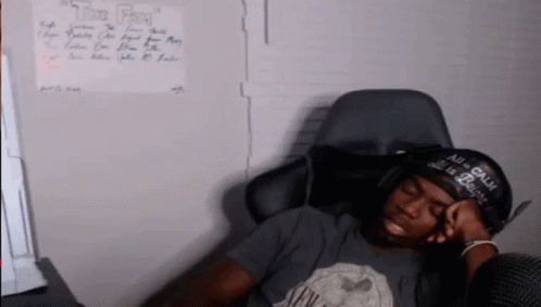 A Man Wearing A Hat That Says " All Is Calm " Is Sleeping In A Chair GIF