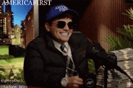 A Man Wearing A Hat That Says America First Is Sitting In Front Of A Microphone GIF