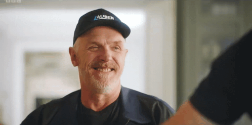 A Man Wearing A Hat That Says ' Auben ' On It Smiles GIF