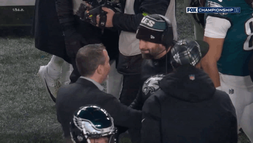 A Man Wearing A Hat That Says Eagles On It Is Surrounded By Other People GIF