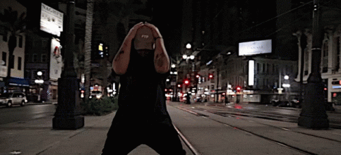 A Man Wearing A Hat That Says Ftp On It Stands On A City Street GIF