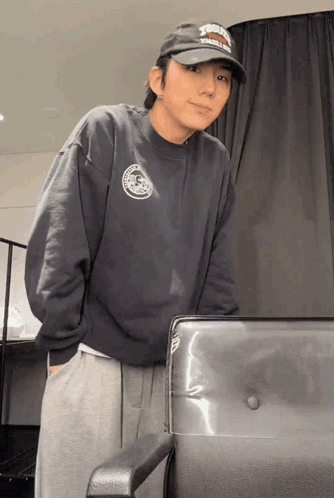 A Man Wearing A Hat That Says ' Harley Davidson ' On It Is Standing Next To A Chair GIF