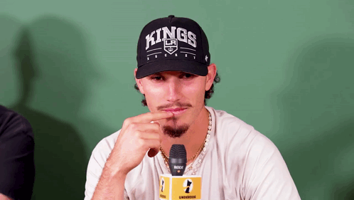 a man wearing a hat that says kings is sitting in front of a microphone