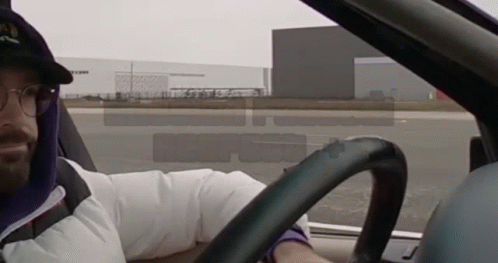 A Man Wearing A Hat That Says ' Nl ' On It Driving A Car GIF