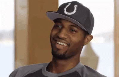 a man wearing a hat with a horseshoe on it is smiling and looking at the camera .