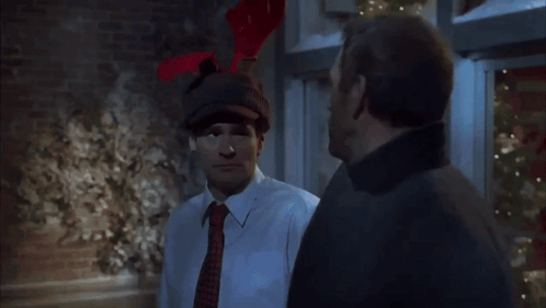 A Man Wearing A Hat With Reindeer Antlers Is Talking To Another Man GIF