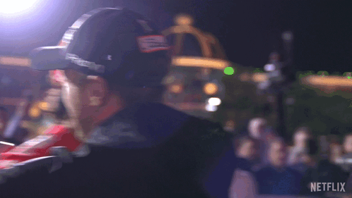 A Man Wearing A Hat With The Letter B On It Is Standing In Front Of A Crowd And A Sign That Says Netflix GIF