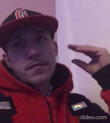 A Man Wearing A Hat With The Letter G On It Is Making A Hand Gesture GIF