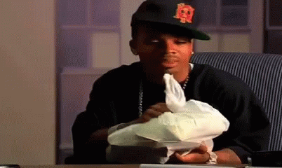 A Man Wearing A Hat With The Letter R On It Is Sitting At A Table Holding A Piece Of Paper . GIF