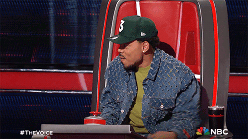 A Man Wearing A Hat With The Number 3 On It Sits In A Chair GIF