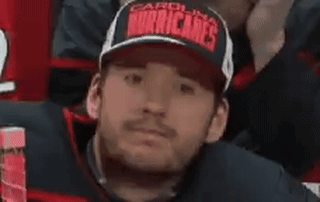 A Man Wearing A Hat With The Word Hurricanes On It Is Sitting In A Stadium . GIF