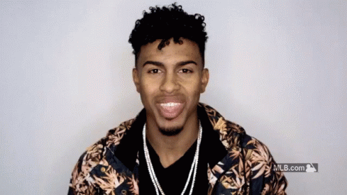 A Man Wearing A Hawaiian Jacket Is Smiling In Front Of A Mlb.com Logo GIF