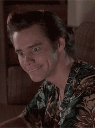 A Man Wearing A Hawaiian Shirt Is Smiling And Looking At The Camera GIF