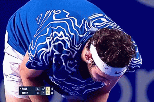 A Man Wearing A Headband And A Blue Shirt Looks Down At A Scoreboard That Says Paul Fritz GIF