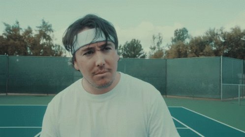 A Man Wearing A Headband And A White Shirt Is Standing On A Tennis Court GIF