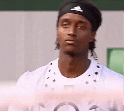 A Man Wearing A Headband And A White Shirt Looks At The Camera . GIF