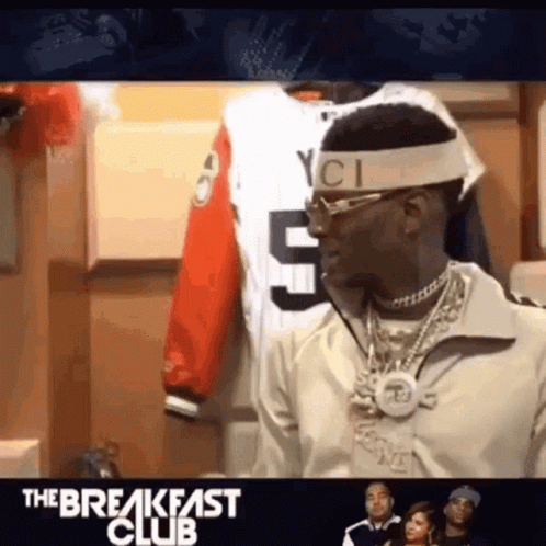 A Man Wearing A Headband And Sunglasses Is Standing In Front Of A Display Of Shirts . GIF