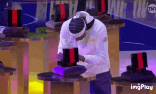 A Man Wearing A Headband Is Sitting At A Table In Front Of A Tnt Sign GIF