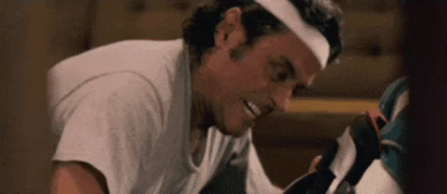 a man wearing a headband is smiling while looking at a pair of shoes .