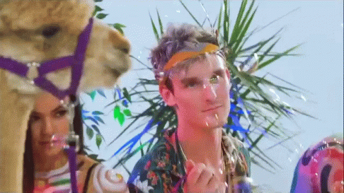 A Man Wearing A Headband Is Standing Next To A Camel . GIF