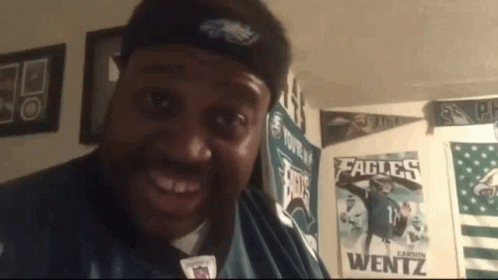 A Man Wearing A Headband That Says Eagles Is Smiling GIF