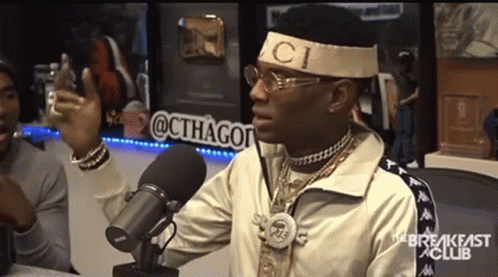 A Man Wearing A Headband That Says Gucci Is Talking Into A Microphone GIF