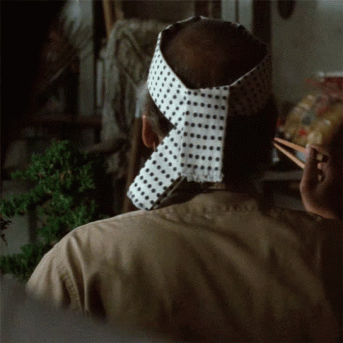 A Man Wearing A Headband With Polka Dots On It Is Holding Chopsticks GIF