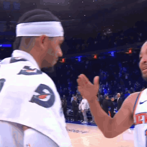 A Man Wearing A Headband With The Letter G On It Talks To Another Man GIF