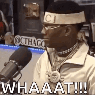 A Man Wearing A Headband With The Word Gucci On It Is Talking Into A Microphone . GIF