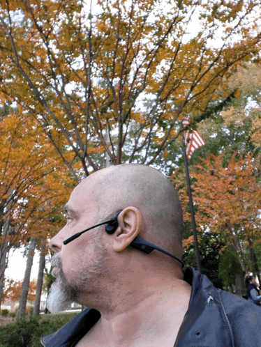 A Man Wearing A Headset Is Standing In Front Of Trees GIF
