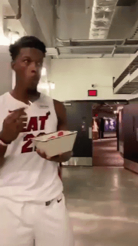 A Man Wearing A Heat Jersey Is Eating Something GIF