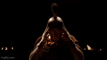 A Man Wearing A Helmet And A Hood Is Looking At The Camera In A Dark Room . GIF