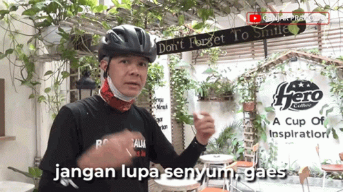 A Man Wearing A Helmet And A Mask Stands In Front Of A Sign That Says Hero Coffee GIF